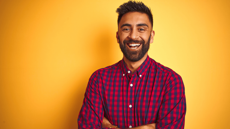 Smiling confident electrician with beard in casual shirt.